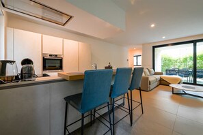 Eine moderne Küche mit Backofen und einem Essbereich mit blauen Stühlen und einer Couch.