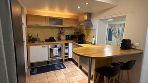 A compact kitchen with a central island, a built-in oven, and a stove. - STUNNING DUPLEX IN THE HEART OF THE CITY CENTER WITH UNDERGROUND PARKING INCLUDED, 10 MINUTES FROM PARIS (Rueil-Malmaison)