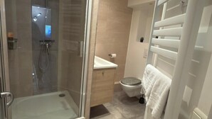 A modern bathroom with a glass shower enclosure, a white sink, and a toilet. - STUNNING DUPLEX IN THE HEART OF THE CITY CENTER WITH UNDERGROUND PARKING INCLUDED, 10 MINUTES FROM PARIS (Rueil-Malmaison)