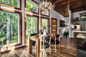 Ein modernes Interieur mit großen Fenstern, einem Essbereich und einer Küche.
