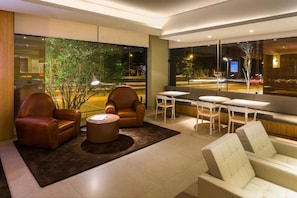 A modern lounge area with leather sofas, a round coffee table, and a view of a street at night.
