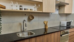 Una cocina con pileta de acero inoxidable, armarios de madera, microondas y horno empotrado.