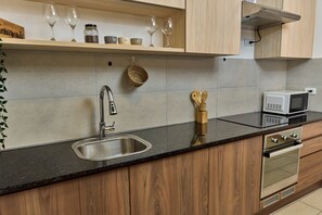 Une cuisine équipée d’un évier en acier inoxydable, de meubles en bois, d’un four à micro-ondes et d’un four encastré.