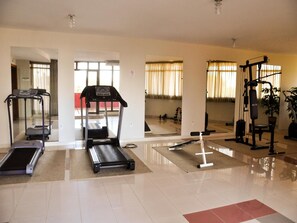 Uma academia com esteiras, bicicleta ergométrica e equipamentos de musculação.