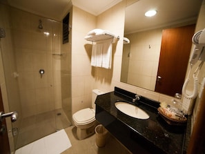 Een badkamer met een douche, toilet, wastafel en een spiegel.