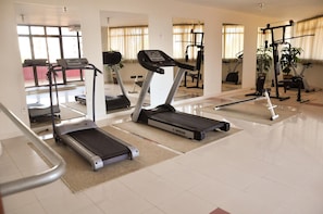 Une salle de sport équipée de tapis de course, de vélos elliptiques et d’appareils de musculation.