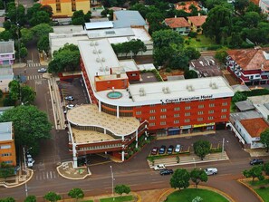 Um hotel com fachada vermelha, telhado curvo e estacionamento.
