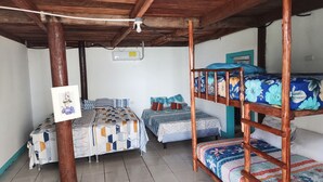 Un dormitorio con literas, una mesa y un ventilador de techo.