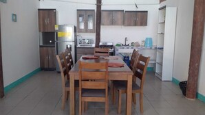 Un comedor con una mesa y sillas de madera, un refrigerador, una estufa y alacenas.