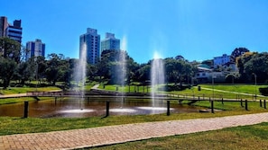 Ein Park mit Springbrunnen, einem gepflasterten Weg und Gebäuden im Hintergrund.