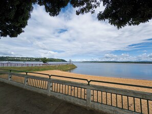 En strand med et hegn, et roligt vandareal og en fjerndrevet kystlinje.