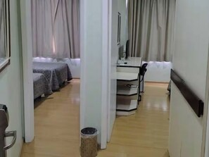 Ein Hotelzimmer mit Bett, Schreibtisch, Stuhl und Mülleimer.