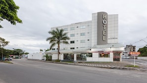 Een hotel met een moderne gevel, een overdekte ingang en een bord waarop 24-uurs service wordt aangegeven.