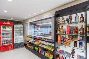 Een winkel met een Coca-Cola koelkast, een glazen vitrine met diverse flessen en snacks, en een raam met uitzicht op een auto.