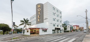 Ein modernes Hotel mit einem großen 'HOTEL'-Schild, einem Restaurant im Erdgeschoss und einem Parkplatz.
