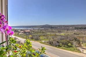 A view from a window overlooking a road with houses and a hilly landscape. - Apartman Posedarje by Aneo Travel (Posedarje)