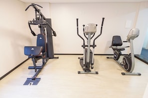 A gym with a stationary bike, elliptical, and weight machine.