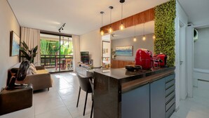 A modern kitchen with a central island, a dining area with a sofa, and a living room with a fan. - Wai Wai #a204 Comfort Beachfront By Carpediem (Caucaia)