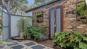 A brick house with a metal door, potted plants, and a gravel pathway. - Away Away - Surf Side Inverloch (Inverloch)
