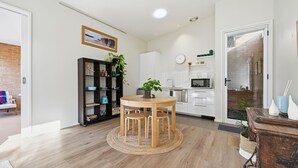 Eine moderne Küche mit einem runden Holztisch, weißen Schränken und einer Ziegelwand.