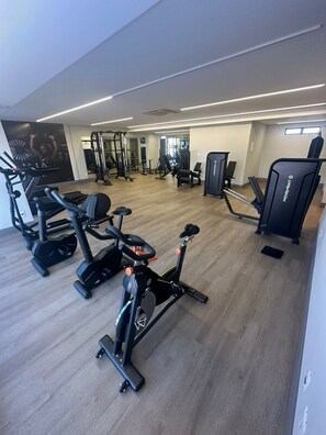 Ginásio com máquinas de cardio, equipamentos de musculação e um painel de espelhos.