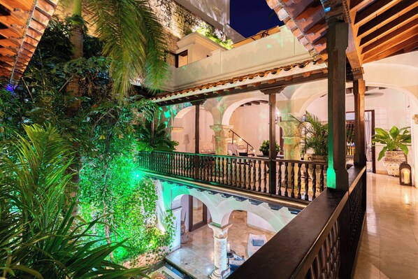 Ein mehrgeschossiges Atrium mit Balkon, Säulen und üppiger Bepflanzung.