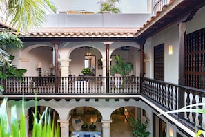 A courtyard with a balcony, arches, and potted plants. - CASA ESTRADA LUXURY VILLA (Cartagena de Indias)