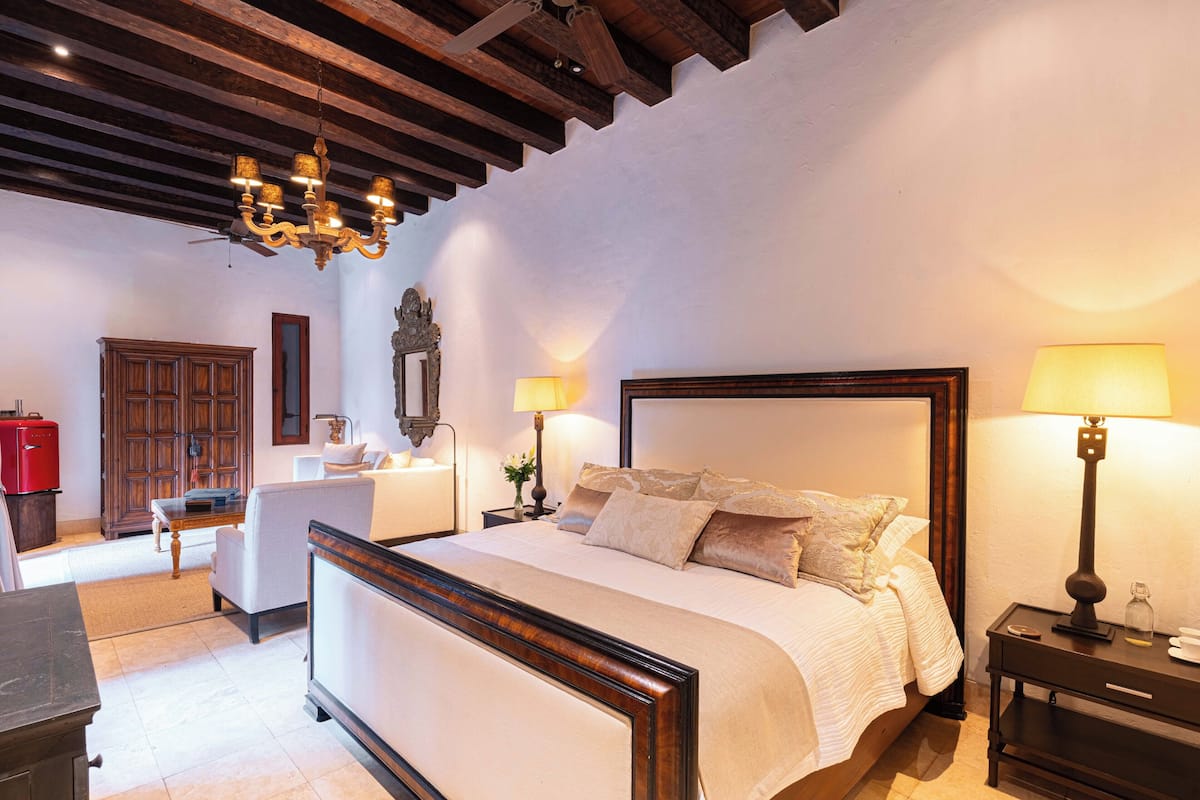 Une chambre à coucher avec un lit en bois, des lampes de chevet, une table de chevet, une commode et un miroir.