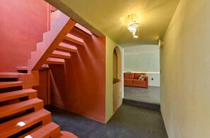 Un escalier menant à un espace de vie comprenant un canapé et une lampe.