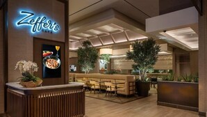 A modern hotel lobby with a reception desk, seating area, and a large potted plant.