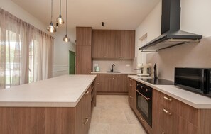 Eine moderne Küche mit Holzausstattung, einer zentralen Kochinsel, einer Mikrowelle und einer Kaffeemaschine.