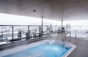 A modern indoor swimming pool with a view of a snowy landscape. - The Corner Stoke by Revelstoke Vacations (Revelstoke)