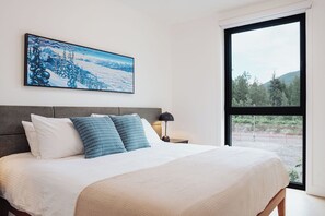 Ein Schlafzimmer mit einem großen Bett, einem Nachttisch, einer Lampe und einem Gemälde an der Wand.