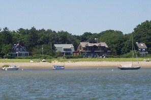 Eine Küstenlandschaft mit Häusern, einem Sandstrand und Booten auf dem Wasser.