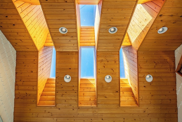 Un plafond en bois agrémenté de lucarnes et d’un éclairage encastré.
