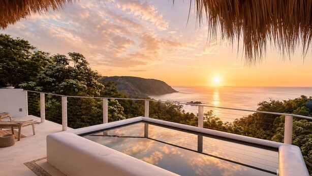 Piscina infinita no terraço com vista para o pôr do sol sobre o oceano.