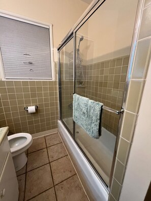Een badkamer met toilet, douche met glazen deur en een handdoekrek.