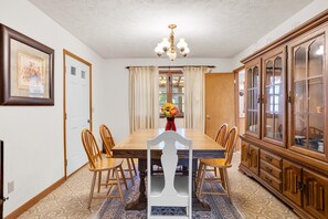 Ein Esszimmer mit Holztisch, Stühlen, einer Chandelier und einem Schrank.