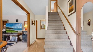 A staircase with carpeted steps, a wooden handrail, and a door with a mirror. - Orchard Ridge Retreat (Flat Rock)