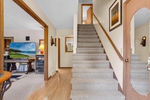 A staircase with carpeted steps, a wooden handrail, and a door with a mirror. - Orchard Ridge Retreat (Flat Rock)