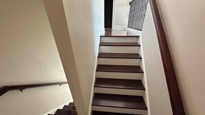 Una escalera con escalones de madera y paredes blancas.