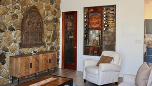 A stone wall, a wine cellar, a white leather armchair, and a wooden cabinet. - Welcome to 30A Glass House — a bright, modern coastal retreat (Santa Rosa Beach)