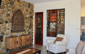 A stone wall, a wine cellar, a white leather armchair, and a wooden cabinet. - Welcome to 30A Glass House — a bright, modern coastal retreat (Santa Rosa Beach)