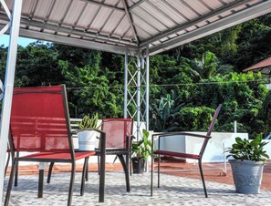 Een overdekt terras met twee rode stoelen en plantenpotten.