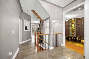 Una escalera con barandas y pasamanos de madera que lleva a una habitación con una puerta.