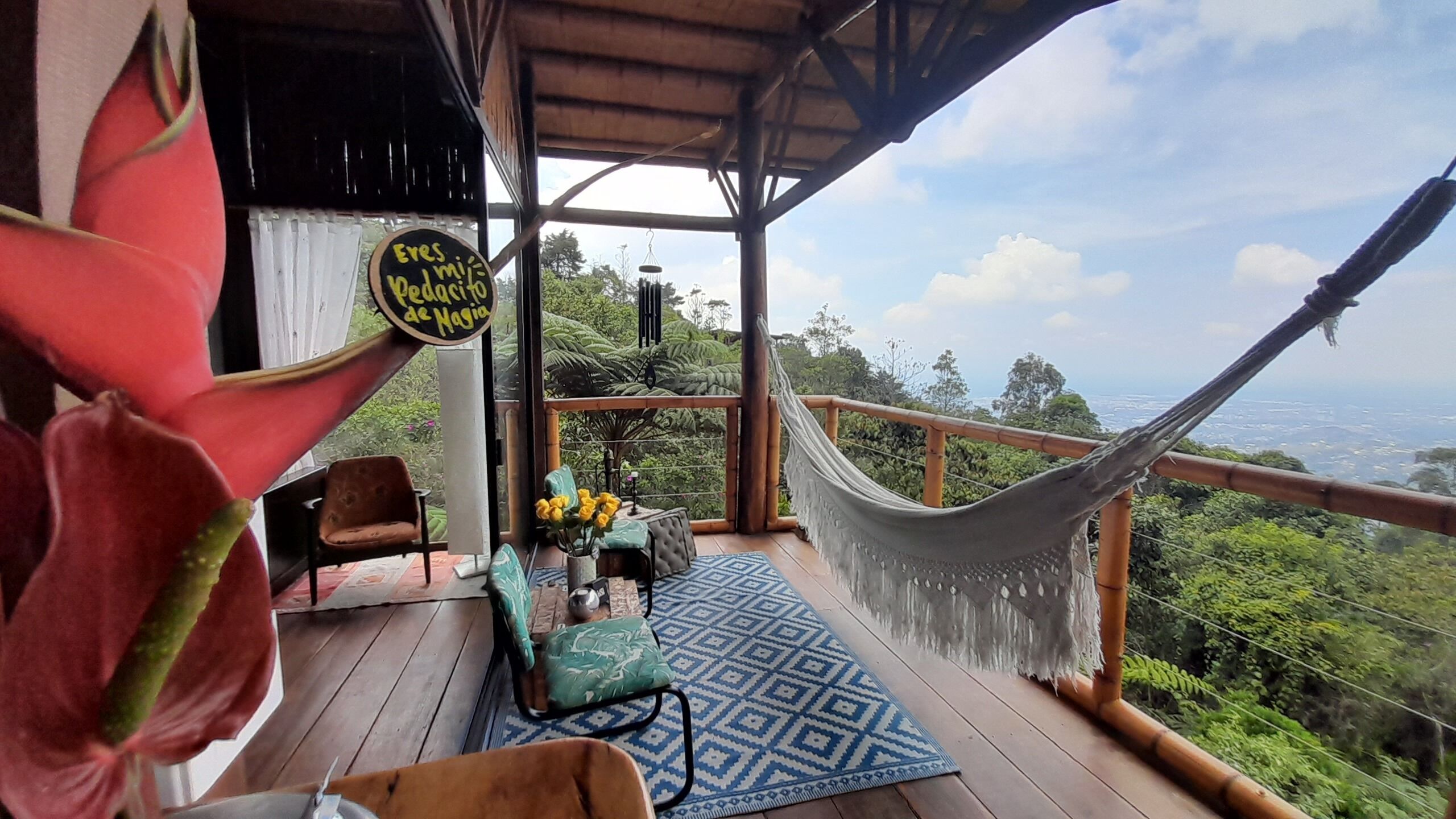 A wooden deck with a hammock, chairs, and a view of the landscape.