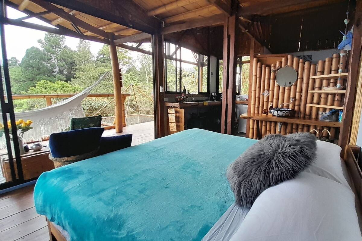 Una habitación con una cama, una mesita y vistas al exterior.