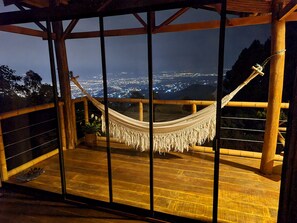 Una hamaca sobre una terraza de madera con vistas a la ciudad.