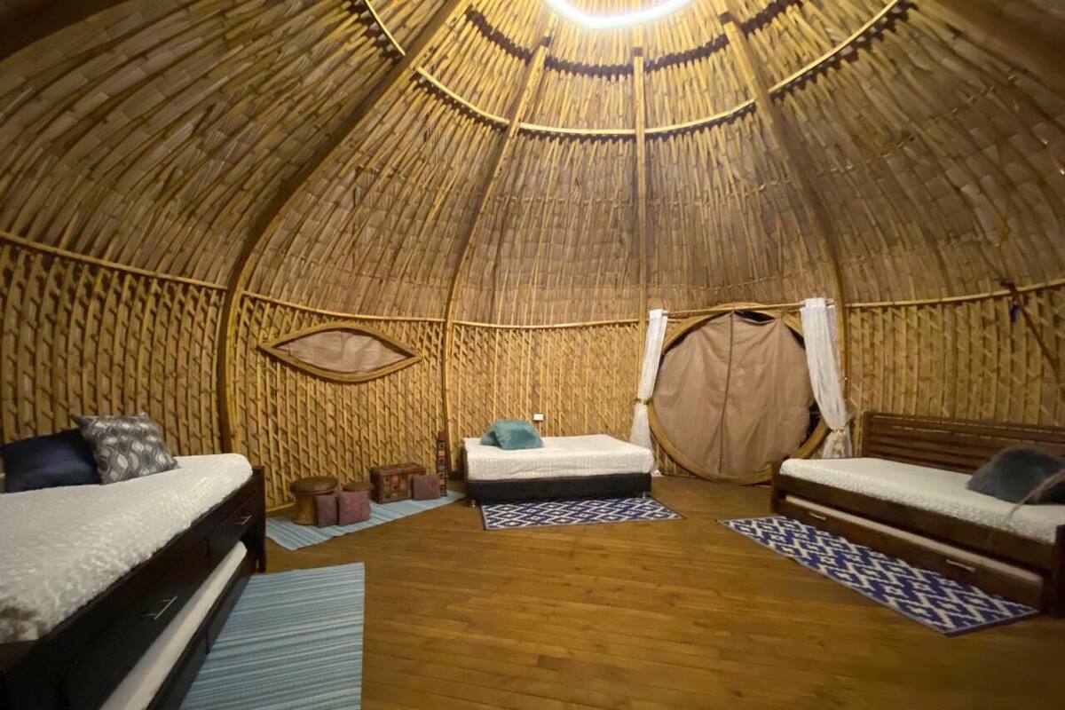 Un interior circular de madera con dos camas, una mesita y un banco.