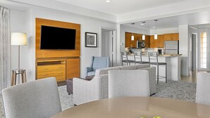 A modern hotel room with a living area, dining space, and kitchenette.